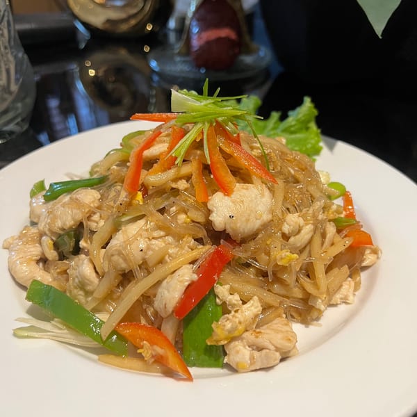 Thai Delight Norman's Pad Woon Sen with chicken, glass noodles, and colorful vegetables on a white plate.